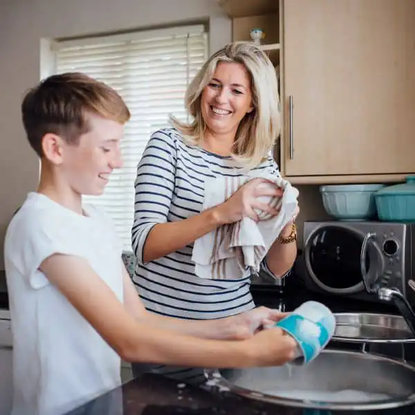 Mother and child washing dishes together at home